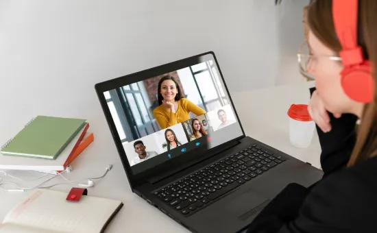 Persona con auriculares frente a un laptop participando en una videollamada